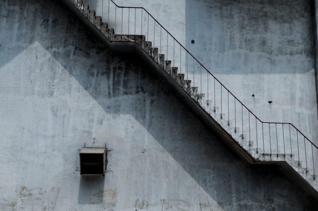 A weathered urban staircase casting dramatic shadows against a concrete wall.